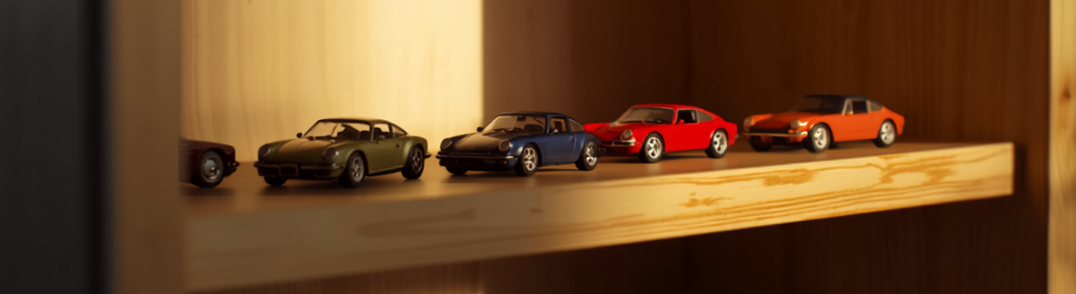 A small shelf display of diecast model cars in warm light