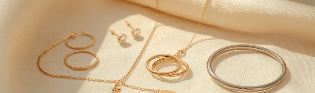 Gold and silver jewelry pieces including rings, a necklace, hoop earrings, and a bangle arranged on soft cream linen for an at-home cleaning and care guide